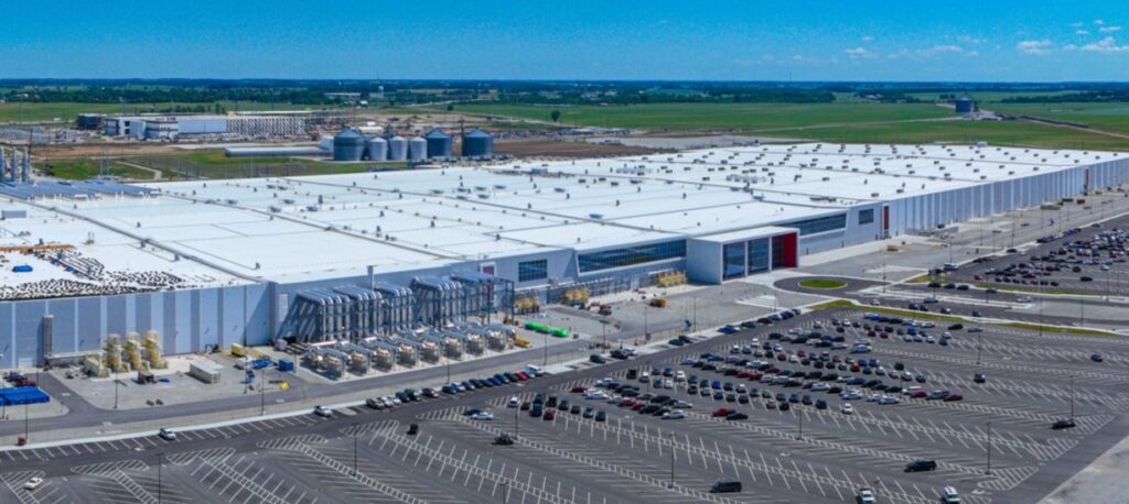 An aerial view of a large white building next to a parking lot.